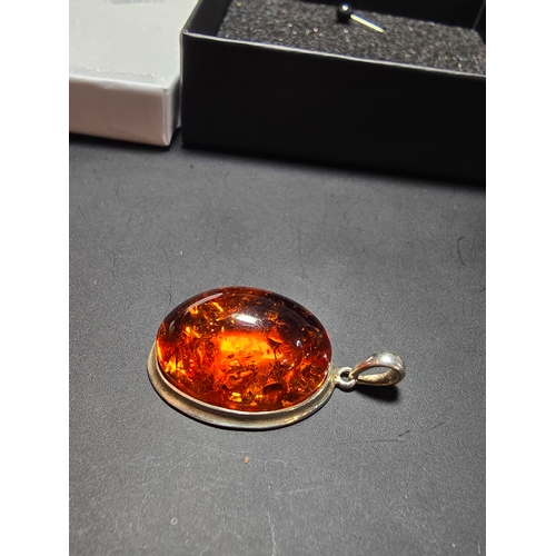 172 - A good quality 925 silver pendant inset with a large oval natural amber stone with inclusions, featu... 