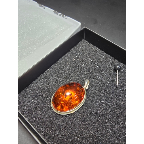 172 - A good quality 925 silver pendant inset with a large oval natural amber stone with inclusions, featu... 