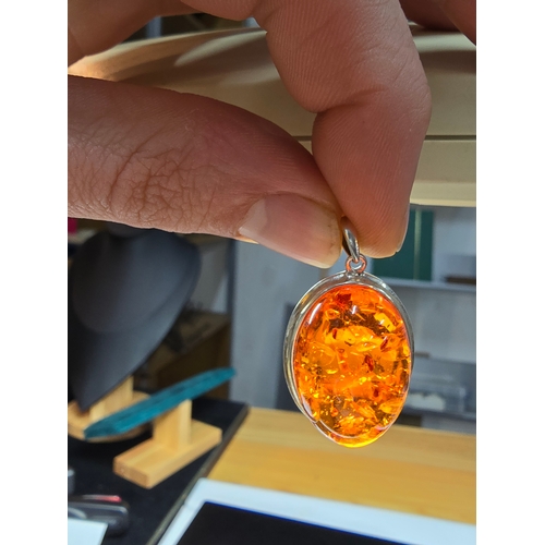 172 - A good quality 925 silver pendant inset with a large oval natural amber stone with inclusions, featu... 