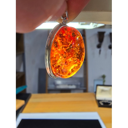 172 - A good quality 925 silver pendant inset with a large oval natural amber stone with inclusions, featu... 