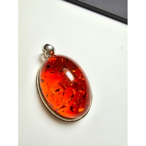 172 - A good quality 925 silver pendant inset with a large oval natural amber stone with inclusions, featu... 