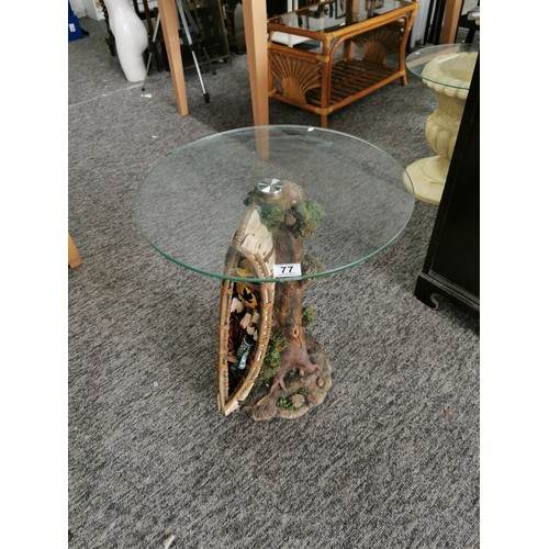 77 - Circular glass topped resin garden table in the form of a tree trunk with an Indian canoe to the sid... 