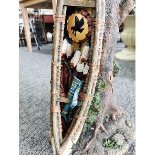 77 - Circular glass topped resin garden table in the form of a tree trunk with an Indian canoe to the sid... 