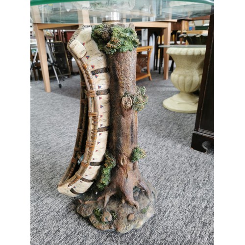 77 - Circular glass topped resin garden table in the form of a tree trunk with an Indian canoe to the sid... 