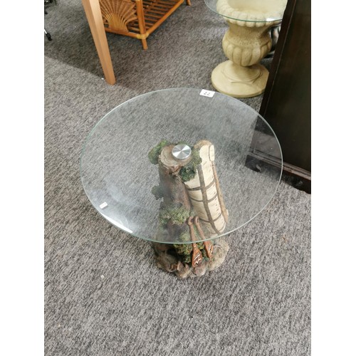 77 - Circular glass topped resin garden table in the form of a tree trunk with an Indian canoe to the sid... 