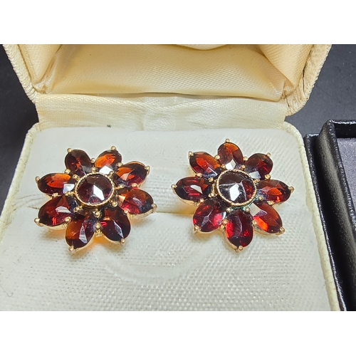 182 - A pair of gold plated dress earrings inset with faceted real garnet gemstones and has a 9ct gold but... 