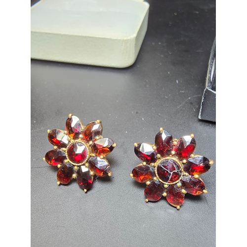 182 - A pair of gold plated dress earrings inset with faceted real garnet gemstones and has a 9ct gold but... 