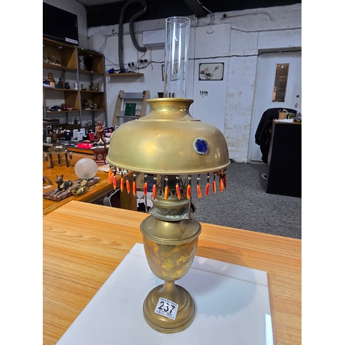 237 - A pretty Antique brass oil lamp featuring a jeweled shade with tassle fringe drops. In good conditio... 