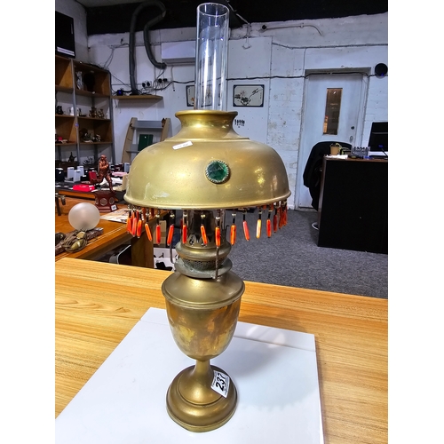 237 - A pretty Antique brass oil lamp featuring a jeweled shade with tassle fringe drops. In good conditio... 