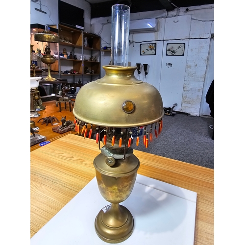 237 - A pretty Antique brass oil lamp featuring a jeweled shade with tassle fringe drops. In good conditio... 