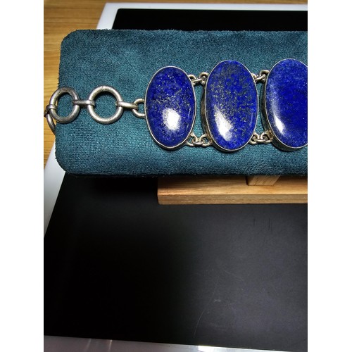 204 - A large 925 silver bracelet inset with 6 large oval lapis lazuli stones presenting vibrant blue natu... 