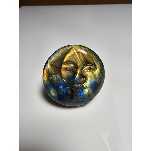 215 - An interesting carved natural labradorite hard stone carved disc with a sun and moon design, present... 