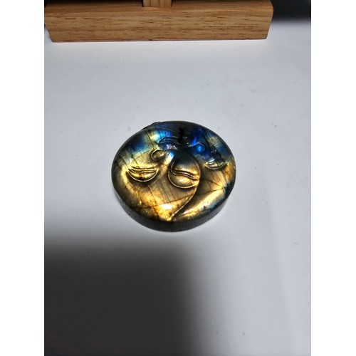 215 - An interesting carved natural labradorite hard stone carved disc with a sun and moon design, present... 