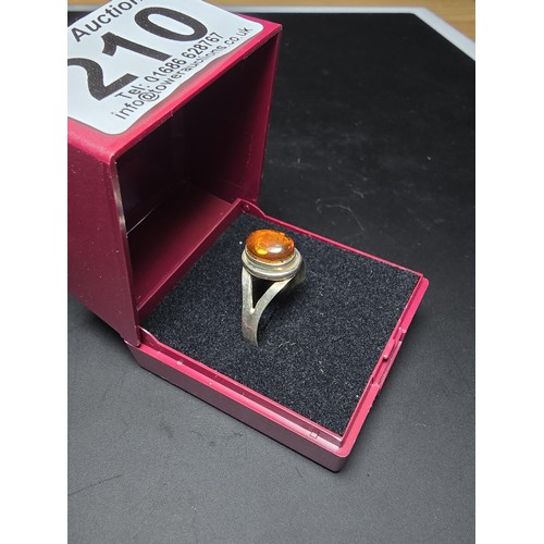 210 - An attractive 925 silver dress ring inset with a large natural Baltic amber cabochon stone. In excel... 