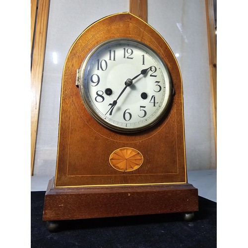 325 - An attractive antique lancet shaped mahogany mantel clock with string inlay and inlay panel to the f... 