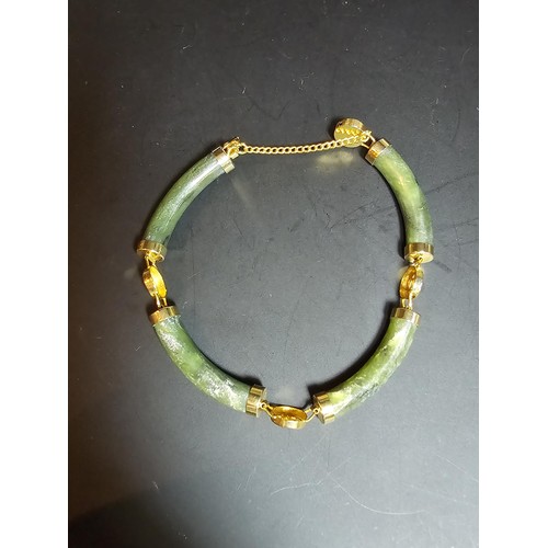 240 - An attractive oriental design bangle featuring green hard stone panels all the way around. Appears t... 