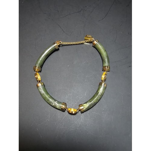 240 - An attractive oriental design bangle featuring green hard stone panels all the way around. Appears t... 