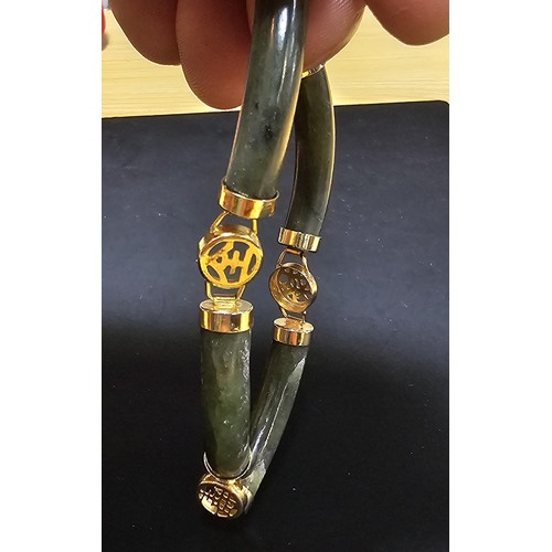 240 - An attractive oriental design bangle featuring green hard stone panels all the way around. Appears t... 