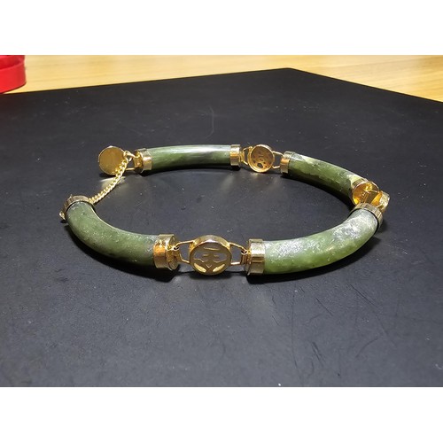 240 - An attractive oriental design bangle featuring green hard stone panels all the way around. Appears t... 