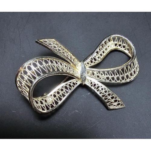 244 - A new and unused 925 silver bow formed brooch with an intricate pierced work design. Has a length of... 