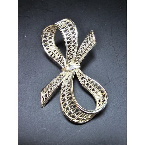 244 - A new and unused 925 silver bow formed brooch with an intricate pierced work design. Has a length of... 