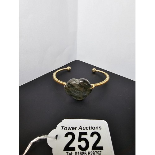 252 - A new and unused gold plated bangle inset with a heart shaped labradorite stone having excellent fla... 