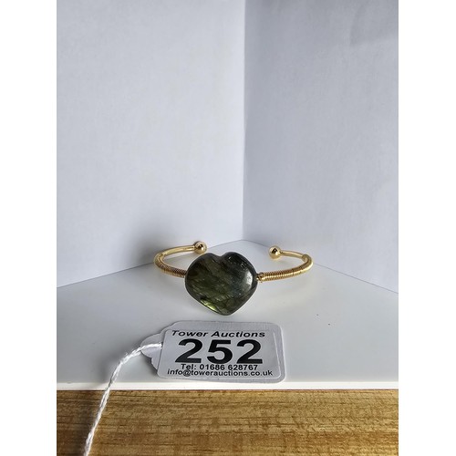 252 - A new and unused gold plated bangle inset with a heart shaped labradorite stone having excellent fla... 