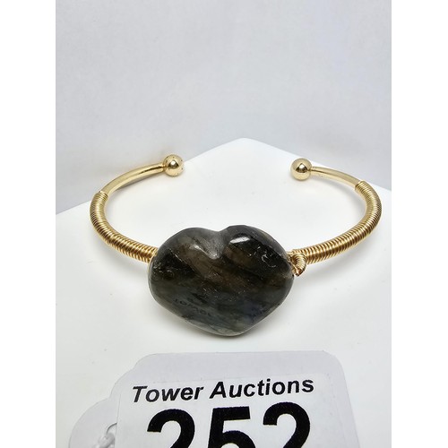 252 - A new and unused gold plated bangle inset with a heart shaped labradorite stone having excellent fla... 