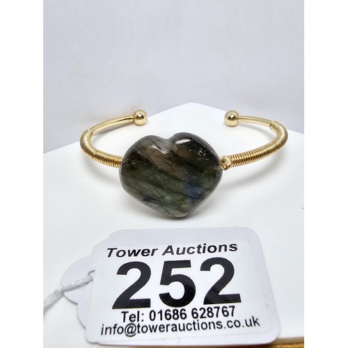 252 - A new and unused gold plated bangle inset with a heart shaped labradorite stone having excellent fla... 