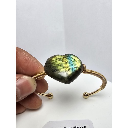 252 - A new and unused gold plated bangle inset with a heart shaped labradorite stone having excellent fla... 