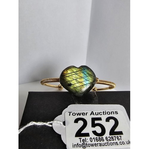 252 - A new and unused gold plated bangle inset with a heart shaped labradorite stone having excellent fla... 