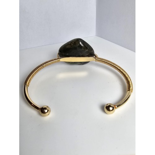 252 - A new and unused gold plated bangle inset with a heart shaped labradorite stone having excellent fla... 