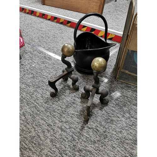 64 - A pair of antique fire dogs with brass balls atop, along with various fireside items, a trivet, bras... 