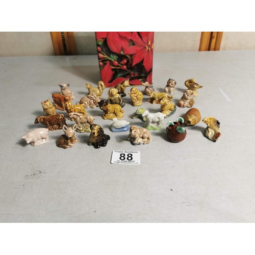 88 - A biscuit tin containing a quantity of Wade Whimsies along with some other small animal figurines.