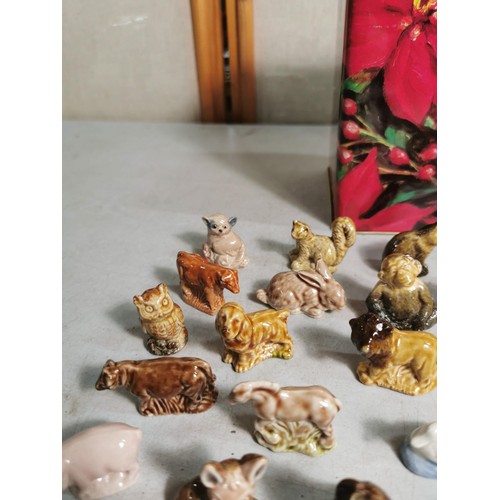 88 - A biscuit tin containing a quantity of Wade Whimsies along with some other small animal figurines.