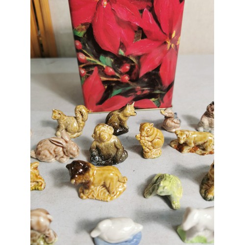 88 - A biscuit tin containing a quantity of Wade Whimsies along with some other small animal figurines.
