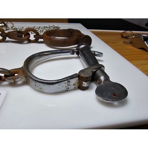 183 - A selection of police related items which includes a pair of vintage chrome handcuffs by Hiatt compl... 