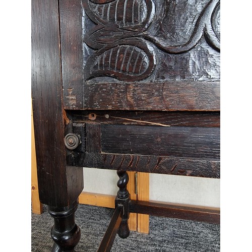 511 - Antique highly carved drinks cabinet with tulip carving to the front and sides, has a pair of pullou... 