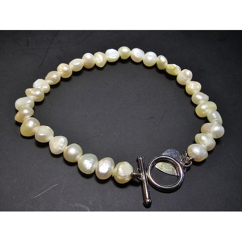 245 - A pretty as new 925 silver and genuine pearl bracelet with a heart charm having a bar and hoop clasp... 