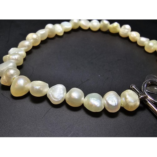 245 - A pretty as new 925 silver and genuine pearl bracelet with a heart charm having a bar and hoop clasp... 