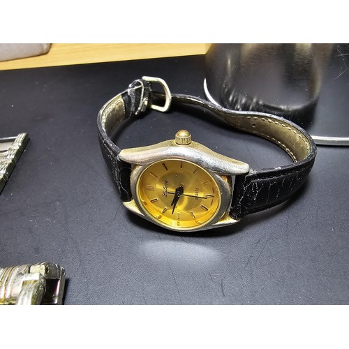 260 - A metal tin containing 4 watches, a watch strap and a Maltese cross belt buckle, the lot includes a ... 