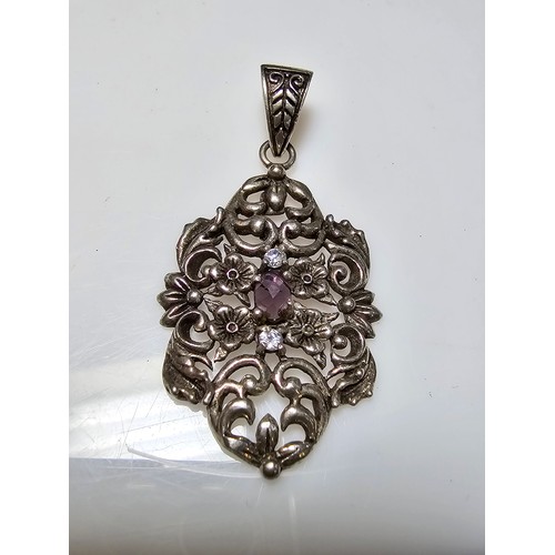 236 - A vintage pretty 925 silver pendant with a pierced floral design inset with a faceted purple glass s... 