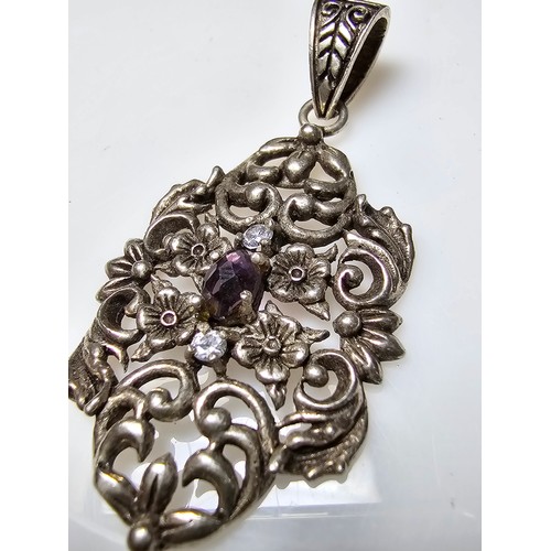 236 - A vintage pretty 925 silver pendant with a pierced floral design inset with a faceted purple glass s... 