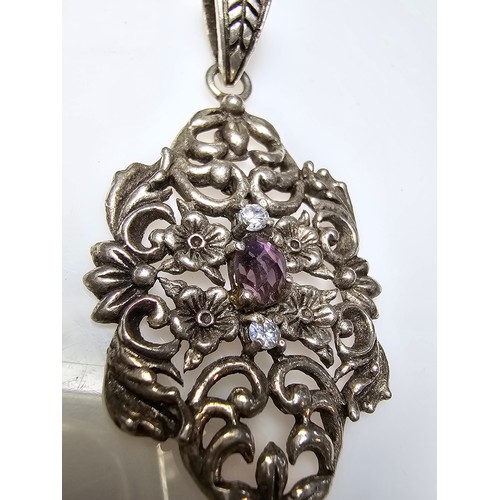 236 - A vintage pretty 925 silver pendant with a pierced floral design inset with a faceted purple glass s... 