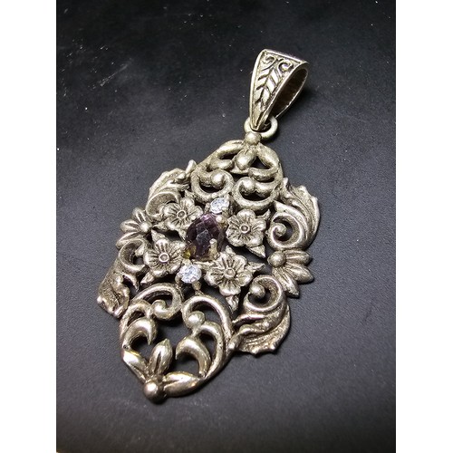 236 - A vintage pretty 925 silver pendant with a pierced floral design inset with a faceted purple glass s... 