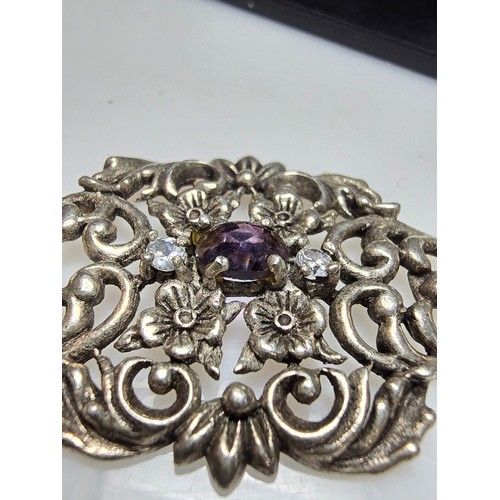 236 - A vintage pretty 925 silver pendant with a pierced floral design inset with a faceted purple glass s... 