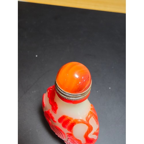 174 - A good vintage carved glass Asian snuff bottle with an agate topped lid with a spoon fitted. The bot... 