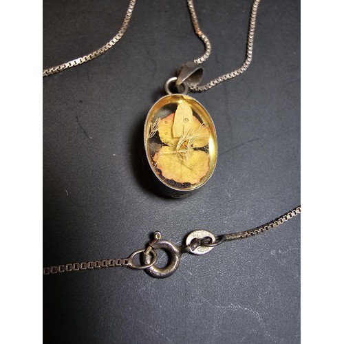 216 - A pretty 925 silver pendant inset with a real dried flower in resin set on an 18