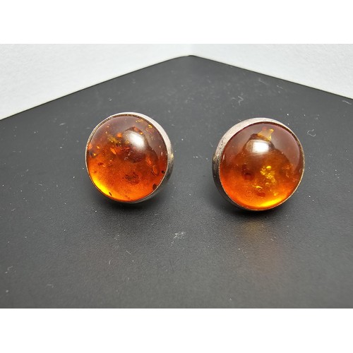 212 - A pair of pretty 925 silver large stud earrings inset with natural Baltic amber stones presenting a ... 