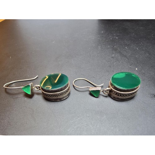 207 - A pair of large ornate and unusual sterling silver drop earrings featuring a polished green glass in... 